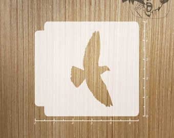 Könnte beinhalten: Eine Holzschablone mit der Silhouette eines fliegenden Vogels. Der Vogel ist mit ausgebreiteten Flügeln dargestellt. Die Schablone ist quadratisch mit abgerundeten Ecken und einem Lineal an der Seite. Der Hintergrund ist ein helles Holzmaserung. Die Schablone ist ca. 12,7 cm groß.
