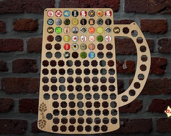 May include: Wooden beer mug-shaped bottle cap holder with a capacity for numerous bottle caps. The holder is made of light-colored wood and features a decorative hop design. The mug is displayed against a brick wall, with some bottle caps already in place.