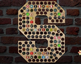 May include: Wooden letter "S" beer cap holder, filled with various colorful bottle caps. The wooden letter is mounted on a brick wall. The image includes a small graphic with the text "OMG Engravings".