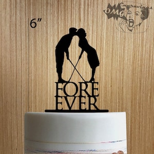 May include: Black silhouette cake topper featuring a couple kissing while holding golf clubs, with the word "FOREVER" below. The topper is 6 inches tall and is placed on a white cake.