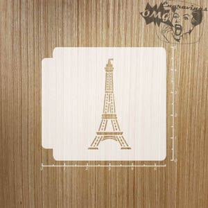 Könnte beinhalten: Eine weiße Schablone des Eiffelturms, ein berühmtes Wahrzeichen in Paris, Frankreich. Die Schablone befindet sich auf einer Holzoberfläche mit einem Lineal, das in Zoll markiert ist.