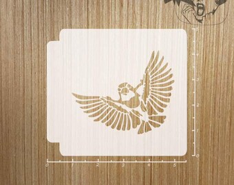 Könnte beinhalten: Eine Holzschablone mit einem Vogel im Flug. Der Vogel ist mit ausgebreiteten Flügeln dargestellt, und die Schablone ist quadratisch mit abgerundeten Ecken. Das Design ist aus dem Holz geschnitten, wodurch ein Negativbild entsteht. Die Schablone ist hellbraun.