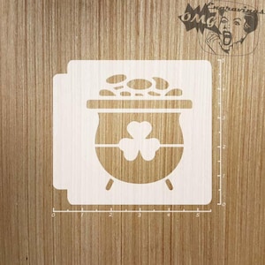 May include: White stencil of a pot of gold with a shamrock on the side. The stencil is on a wooden surface.