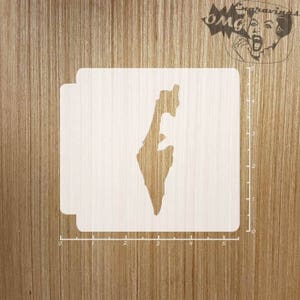 May include: A white stencil of the outline of Israel. The stencil is on a wooden surface with a ruler marked in inches.