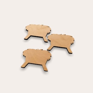 May include: Three wooden cutout manger shapes, each with a simple design of a manger with hay. The manger shapes are brown and have a rustic look.