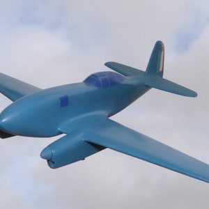 Könnte beinhalten: Ein blaues Flugzeugmodell mit einer französischen Flagge am Heck. Das Flugzeug befindet sich im Flug vor einem bewölkten Himmel.