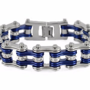May include: A silver and blue chain bracelet with clear rhinestones. The bracelet is made of metal and has a double row of chain links.