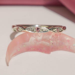 Anillo fino de plata con piedras de cristal de circonita rosa.