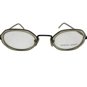 May include: Black oval-shaped eyeglasses with a Giorgio Armani logo on the right lens.