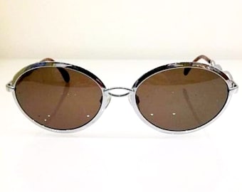 May include: Silver framed oval sunglasses with brown lenses.