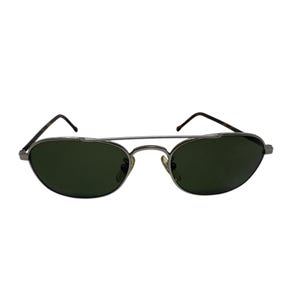 May include: Oval-shaped sunglasses with dark green lenses and a silver metal frame. The sunglasses have a double bridge design and thin temples. The lenses are slightly curved, offering a classic and stylish look.