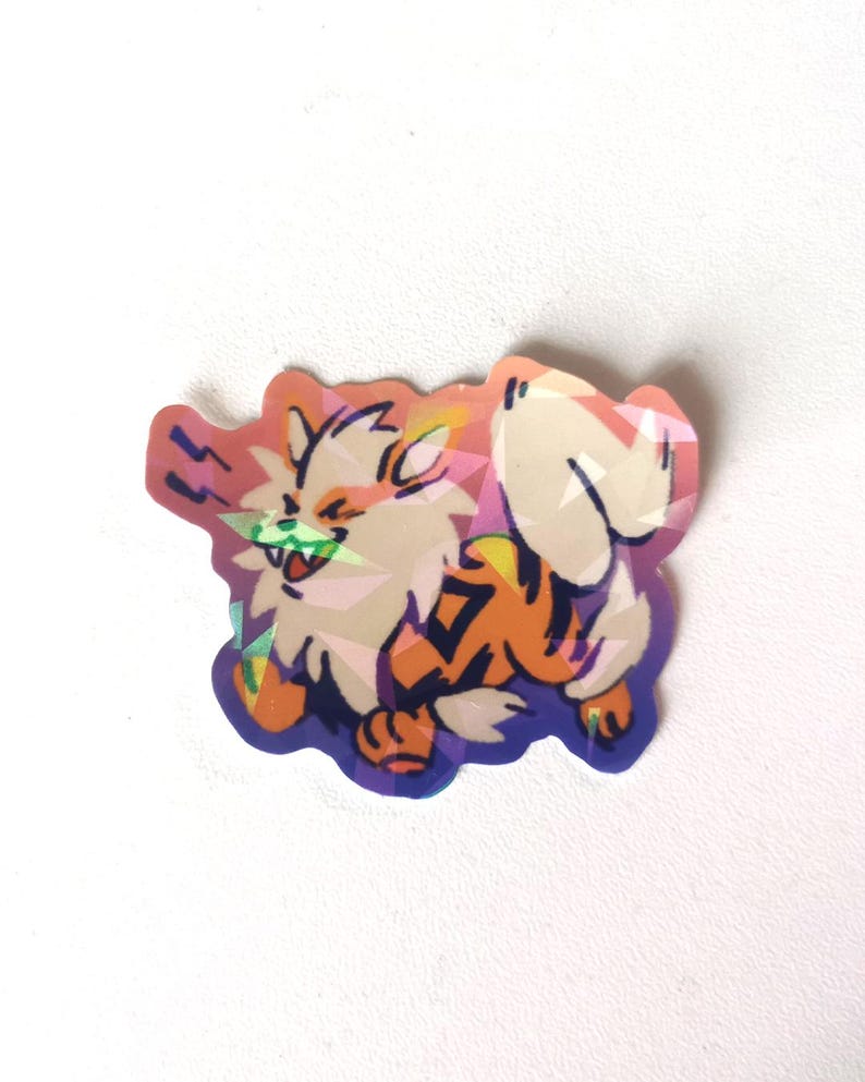 Może przedstawiać: Kolorowa naklejka przedstawiająca postać z kresk&oacute;wki Arcanine. Naklejka ma biały, pomarańczowy i czarny wz&oacute;r z fioletowym obrysem. Postać uśmiecha się z zielonym językiem. Naklejka ma efekt holograficzny.
