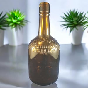 May include: A brown glass bottle with a gold label that reads "W.L. Weller & Son Distillers Louisville, KY".
