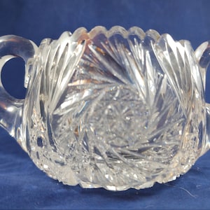 Puede incluir: Un azucarero de vidrio transparente con dos asas. El tazón tiene un diseño de vidrio cortado con un patrón de estrella.