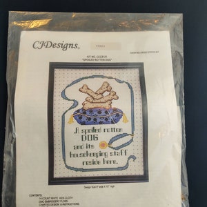 May include: A counted cross stitch kit featuring a dog with bones and a stethoscope. The kit includes 14-count white Aida cloth, DMC embroidery floss, charted design and instructions, and a needle. The design size is 20.3 cm wide by 25.4 cm high. "A spoiled rotten dog and its housekeeping staff reside here."