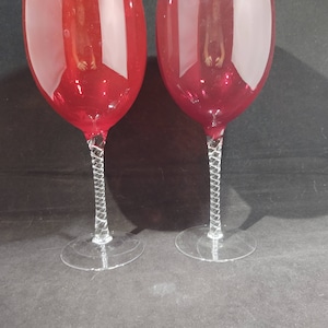 May include: Two red wine glasses with twisted stems. The glasses are empty and have a clear, reflective surface.