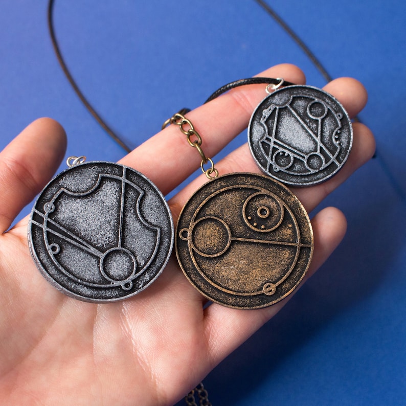 May include: Three silver and gold pendant necklaces with intricate circular designs. The pendants feature a silver, gold, and a silver design.