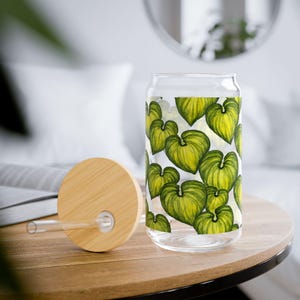Peut inclure: Un verre à boire clair en forme de canette avec un couvercle et une paille en bambou. Le verre est décoré d'un motif de feuilles vertes en forme de cœur. Le couvercle et la paille sont en bambou naturel.