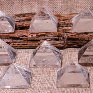 Peut inclure: Neuf pyramides en cristal de quartz clair disposées en rangée sur un fond de toile de jute brune. Les pyramides sont toutes de la même taille et de la même forme, et elles sont toutes tournées vers l'appareil photo.