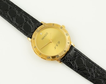 Reloj vintage Imado para mujer en su caja original, esfera dorada, bisel romano y correa de piel.