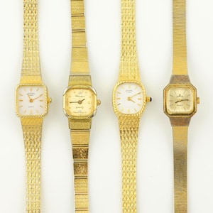 Puede incluir: Cuatro relojes de pulsera dorados con varias formas de esfera y estilos de correa. Los relojes tienen esferas blancas o doradas con manecillas y marcadores negros. Las correas son de malla o de eslabones. Las esferas muestran las marcas "Rotary" y "Lotus".