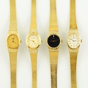 May include: Four gold-coloured wristwatches with mesh straps are displayed against a white background. The watch faces vary in colour, including gold and black, and feature different brand names. The watches are a classic accessory.
