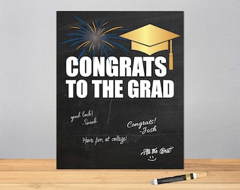 May include: Black chalkboard sign with white text that says "Congrats to the Grad". The sign has a gold graduation cap and blue and yellow fireworks drawn on it. There are handwritten messages on the sign that say "good luck! -Sarah", "Congrats! -Josh", "Have fun at college!" and "All the Best!"