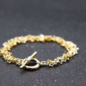 May include: A gold bracelet with a star-shaped chain and a toggle clasp.