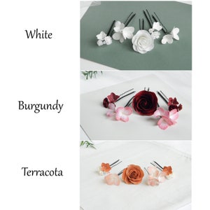 May include: Three sets of floral hair pins in white, burgundy, and terracotta. Each set includes a variety of flower designs, including roses and smaller blossoms, attached to black bobby pins. The word "White", "Burgundy", and "Terracotta" are written in the image.
