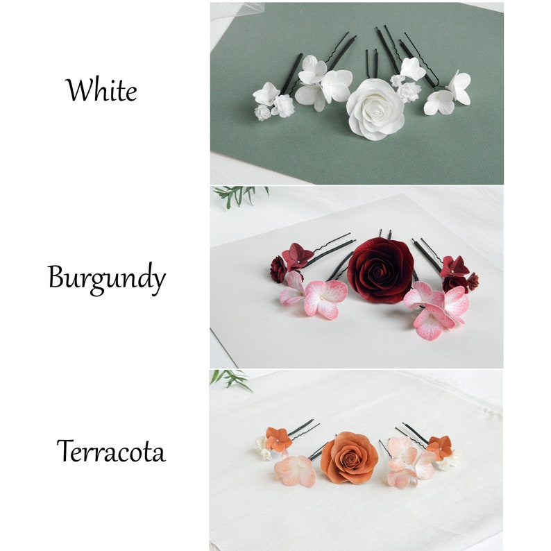 May include: Three sets of floral hair pins in white, burgundy, and terracotta. Each set includes a variety of flower designs, including roses and smaller blossoms, attached to black bobby pins. The word "White", "Burgundy", and "Terracotta" are written in the image.