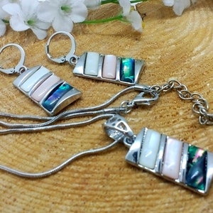 May include: A silver chain necklace with a pendant and matching earrings. The pendant and earrings feature a rectangular design with multiple iridescent shell pieces in shades of white, pink, and green.