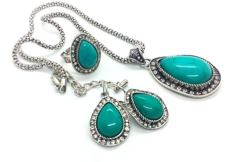 May include: A turquoise gemstone jewellery set with a necklace, ring, and earrings. The set features silver-toned metal with a teardrop-shaped design.
