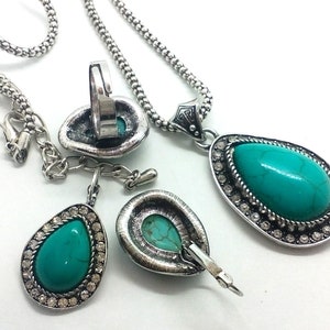 May include: A turquoise stone jewellery set with a necklace, earrings, and a ring. The stones are set in silver-toned metal with clear rhinestones.