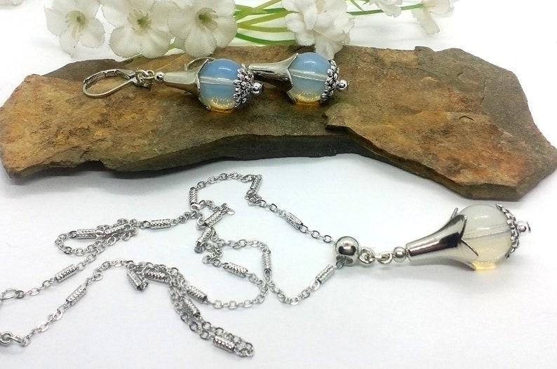 Puede incluir: Un collar de cadena de plata con un colgante en forma de l&aacute;grima con una piedra clara que parece una &oacute;palo. El colgante tiene un dise&ntilde;o de filigrana de plata. Tambi&eacute;n se incluyen pendientes a juego con un dise&ntilde;o similar en forma de l&aacute;grima.