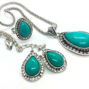 May include: A turquoise stone necklace, ring, and earrings set with silver accents. The stones are set in a teardrop shape and surrounded by clear rhinestones.