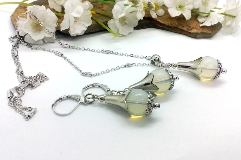 Puede incluir: Un collar de cadena de plata y pendientes a juego con un colgante de &oacute;palo en forma de l&aacute;grima. El colgante est&aacute; engastado en un dise&ntilde;o de flor de plata.
