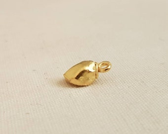 Puede incluir: Un pequeño colgante en forma de corazón de color dorado con una superficie texturizada y un bucle para sujetar una cadena.