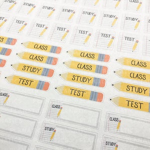 K&ouml;nnte beinhalten: Ein Blatt mit bunten Aufklebern mit Bleistift-Design. Die Aufkleber haben die W&ouml;rter "Klasse", "Studium" und "Test" auf sich.