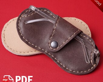 May include: A brown leather eyeglass case with a flap closure and a snap button. The case is open and a pair of clear glasses are inside.