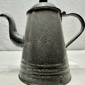 Könnte beinhalten: Vintage graue Emaille-Kaffeekanne mit schwarzem Griff, Ausguss und Deckel. Die Kanne hat ein gesprenkeltes Muster und ein klassisches Design, perfekt für die Kücheneinrichtung oder den Gebrauch.