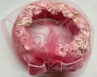 May include: A pink velvet hat with a floral design and a bow. The hat is made of a soft, delicate fabric and is perfect for a special occasion.