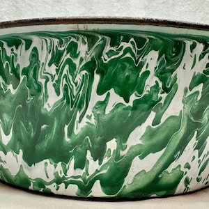 May include: A large, vintage enamelware bowl with a green and white swirled pattern. The bowl has a dark rim and two black handles. The interior and exterior are decorated with the same marbled design.