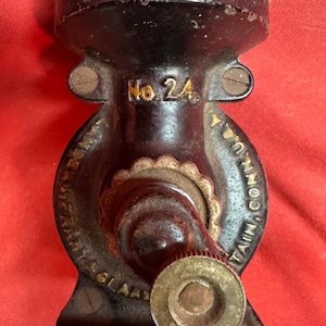 Op de afbeelding: Een zwarte gietijzeren Universal No. 24 voedselmolen met een handzwengel. De metalen behuizing is voorzien van reliëftekst met Universal, No. 24 en Landers, Frary & Clark, New Britain, Conn. U.S.A. Het oppervlak vertoont tekenen van slijtage.