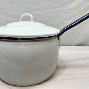 May include: White enamel saucepan with a blue rim and handle. The lid is also white with a blue rim.