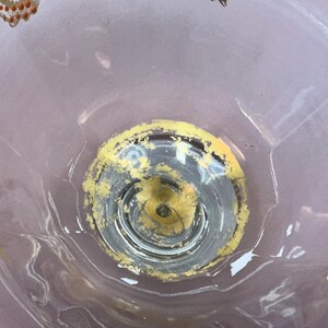 May include: A clear glass bowl with a decorative design. The bowl has a circular base with a yellow and gold rim. The bowl's interior features gold and yellow painted butterfly accents. The bowl has a light purple background.
