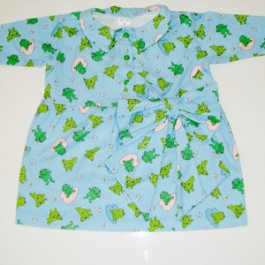 Puede incluir: Un vestido azul claro con estampado de ranas verdes y un lazo en la cintura.