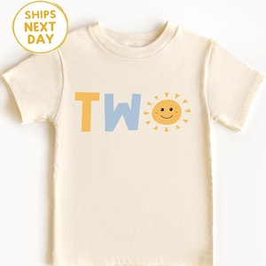 Puede incluir: Camiseta crema para ni&ntilde;os peque&ntilde;os con la palabra "TWO" en amarillo y azul claro, y un gr&aacute;fico de sol sonriente. La camiseta tiene mangas cortas y cuello redondo. El texto "SHIPS NEXT DAY" est&aacute; en un c&iacute;rculo amarillo.
