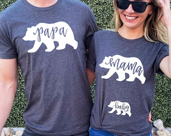 Peut inclure: Un ensemble de trois t-shirts gris avec des silhouettes d'ours blanches et les mots "papa", "mama" et "bébé".