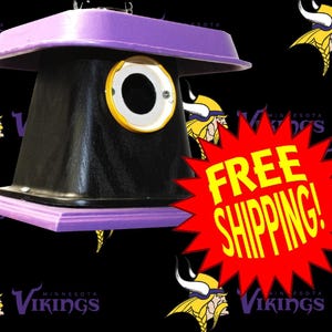 May include: A black and purple birdhouse with a circular entrance and a yellow trim. The birdhouse has a purple roof and base. The Minnesota Vikings logo is in the background.