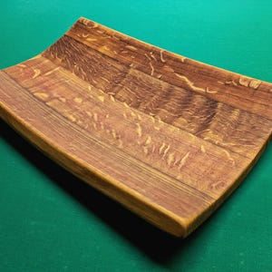 Könnte beinhalten: Ein Serviertablett aus Holz, hergestellt aus wiederverwendeten Weinfassdauben. Das Tablett hat eine natürliche Holzoptik und eine geschwungene Form.